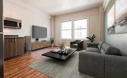 A modern living room with a grey couch, a coffee table, and a large window.