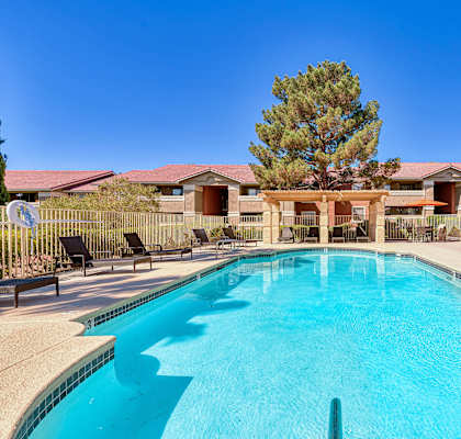 A swimming pool in a residential area with houses and trees in the background.