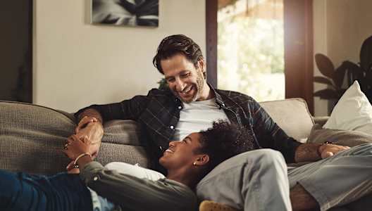a man and woman laughing on a couch