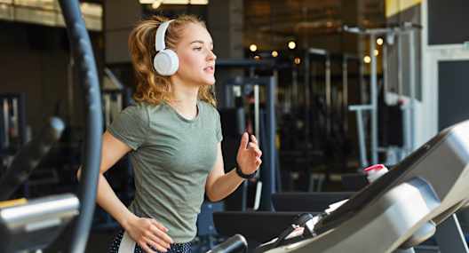 A woman is running on a treadmill in a gym.