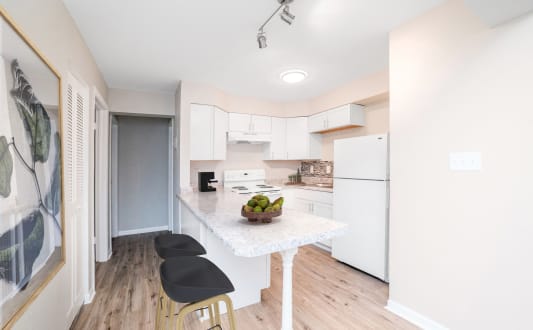 A kitchen with a white fridge, black stools and a marble table. at The Alpine Apartments, Kettering, Ohio