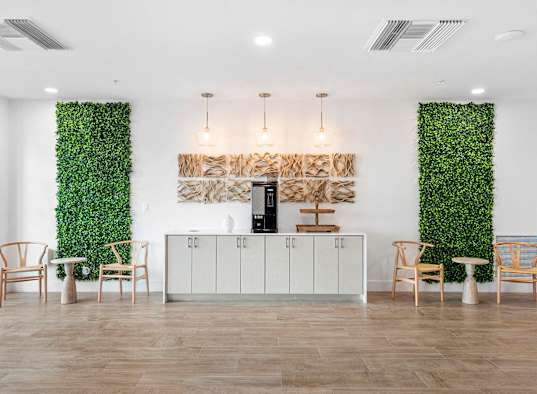 a reception area with a white wall covered in green plants