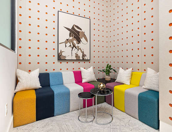 a living room with colorful couches and a painting on the wall