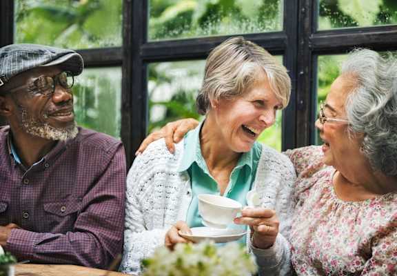 Three people are sitting at a table, enjoying a cup of tea together.