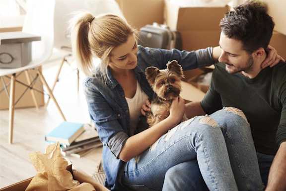 Young couple unpacking and holding their small dog in their new pet-friendly, luxury apartment at South Falls Tower, Richmond, VA, 23224