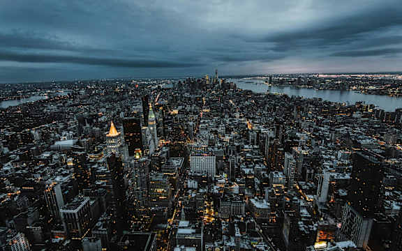 A cityscape at dusk with the Empire State Building prominently lit up.