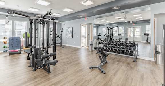 A spacious gym with a variety of equipment including treadmills, weights, and a bench press.