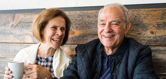 Social senior living at Sage 5430: couple laughing and enjoying coffee near Duluth and Alpharetta