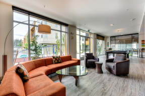 Community Clubhouse Lounge with Orange Sofas, Glass Table and Pool Table in the Distance