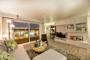 Living Room with Hardwood Inspired Floor, Gray Sofa, Television and Patio Door Leading to Night Sky View