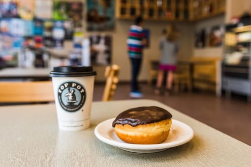 a donut and a cup of coffee sit on a table in a coffee shop