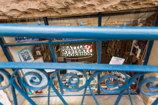 a blue railing in front of a bookstore with a sign that says seattle mystery bookshop