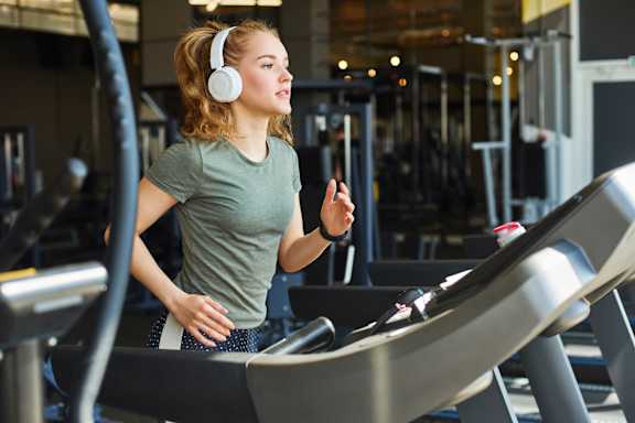 A woman is running on a treadmill in a gym.