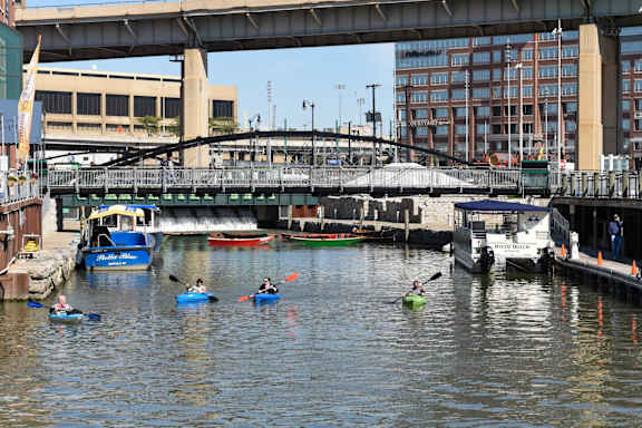 people kayaking on a river in a city