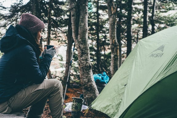 a person sitting in front of a tent with a cell phone