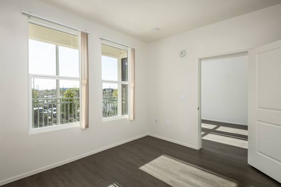 a living room with two windows and a door to a balcony
