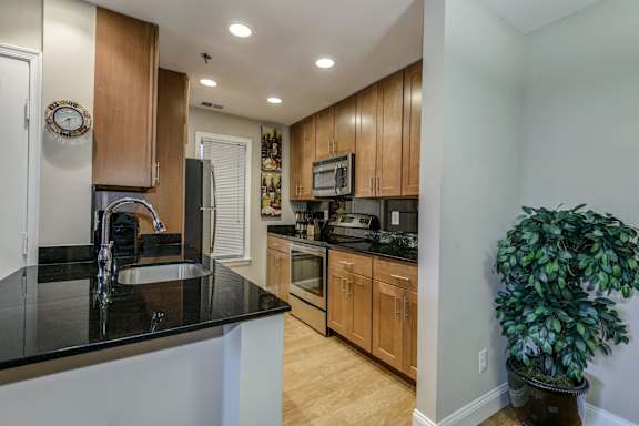 A kitchen with wooden cabinets and black countertops.