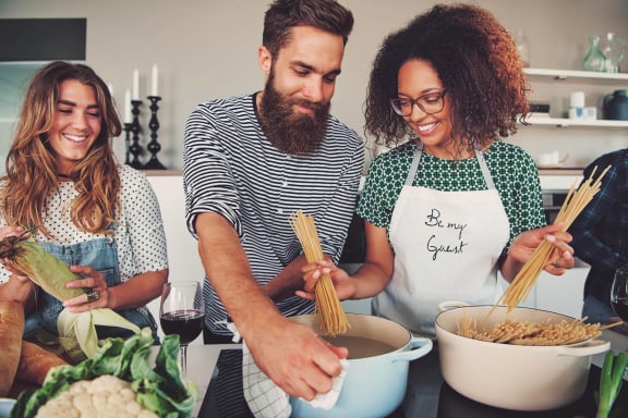 a man and two women making pasta in a kitchen at Aria Landings, Florida