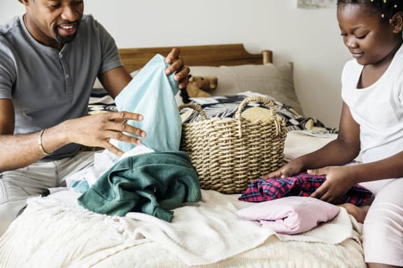 a man and woman sitting on a bed sorting clothes into a basketat Mill Creek Place, Douglasville, GA