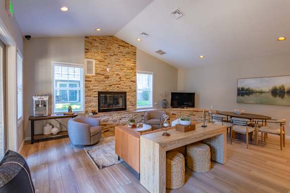 A modern living room with a stone fireplace and wooden furniture.