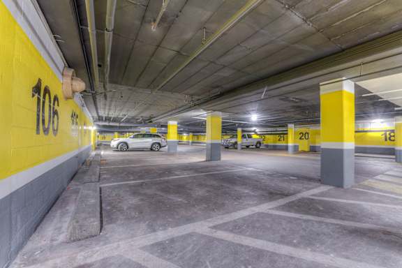A parking garage with yellow walls and a car parked in the 106 spot.at Iris Luxury Apartments, Tennessee