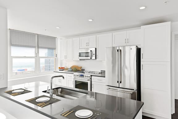 A modern kitchen with a stainless steel refrigerator and grey cabinets.