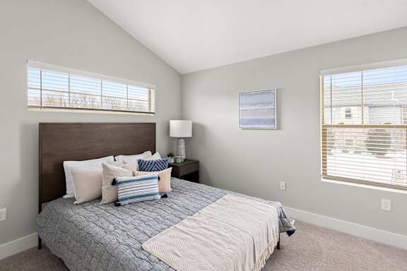 Spacious bedroom with two windows at Quarry Apartments and Townhomes in DeWitt, Michigan