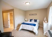Thumbnail 2 of 5 - A bedroom with a bed, nightstand, and chair.