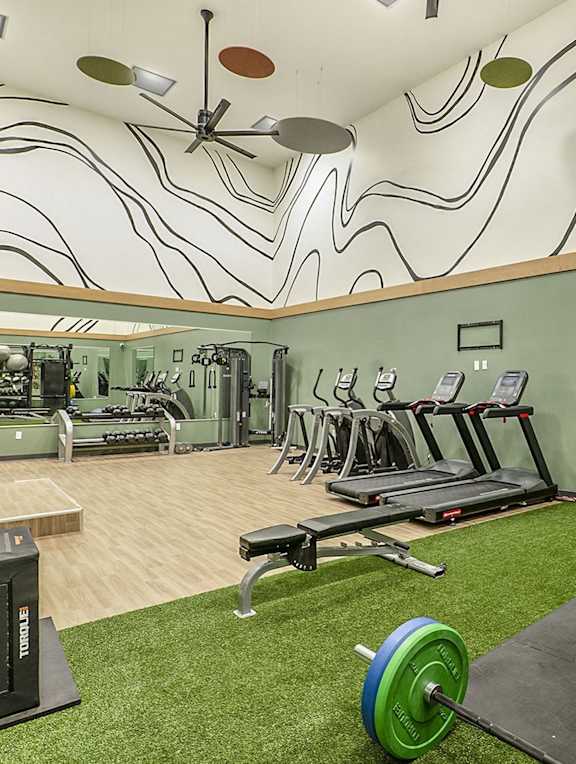 A gym with a green weight and a mirror.