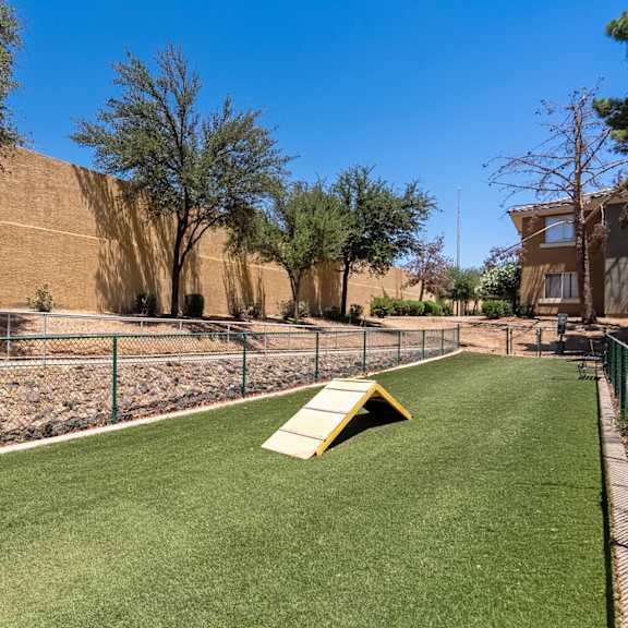 A playground with a yellow slide and green grass.