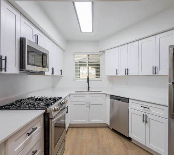 A kitchen with white cabinets and a black stove top.