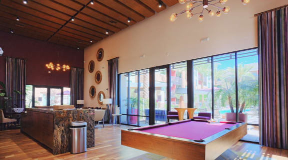 A pool table is in the middle of a room with a wood floor and a wall of windows at Audere Apartments, Arizona, 85016