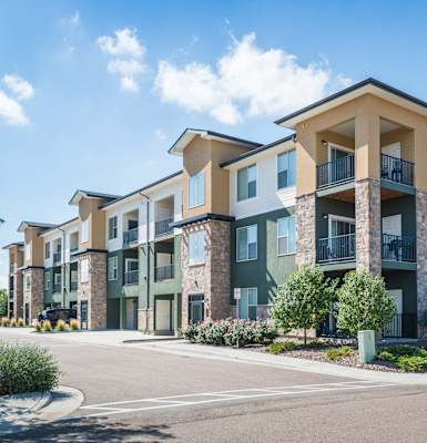 A row of modern apartment buildings with balconies and green front yards. at Arterra Place Apartments, Aurora, CO, 80017