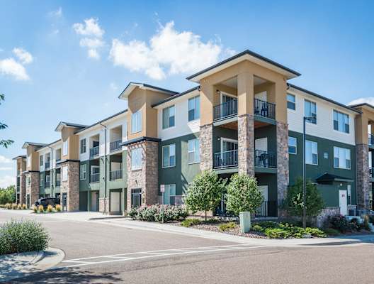 A row of modern apartment buildings with balconies and green front yards. at Arterra Place Apartments, Aurora, CO, 80017