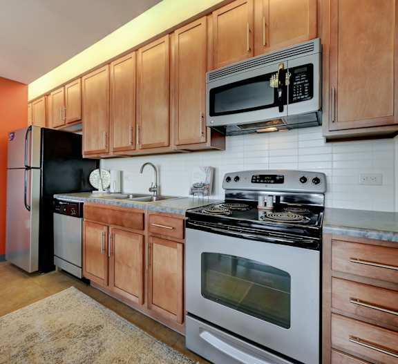 A kitchen with wooden cabinets and a black fridge at Parkhaus Apartments, Lincoln, NE