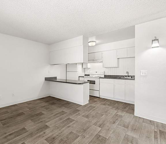 A kitchen with white cabinets and a wooden floor.