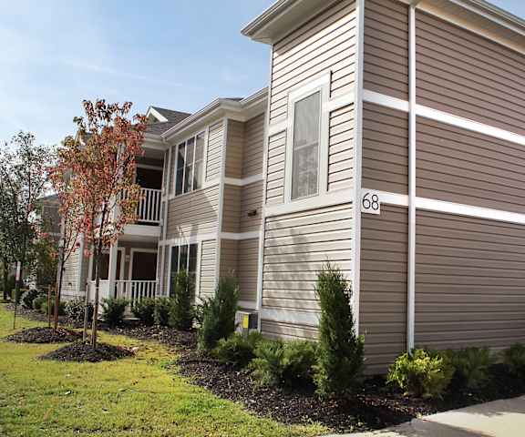 an apartment building with brown siding and a sidewalk