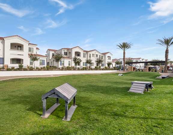 A park with a bench and a picnic table in front of apartment buildings.