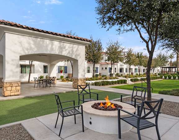 A patio with a fire pit and chairs.