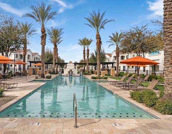 A large pool surrounded by palm trees and sun loungers.