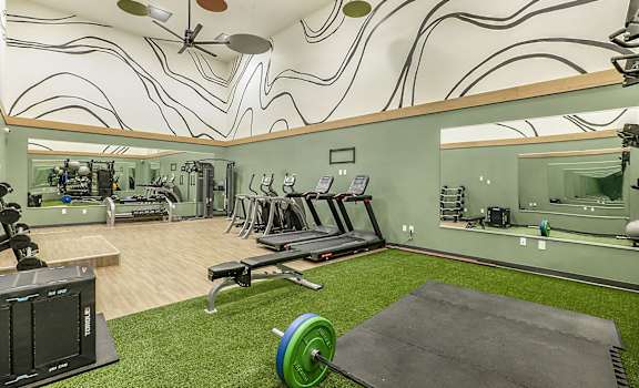 A gym with a green weight and a mirror.