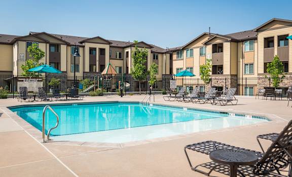 our apartments have a swimming pool with chairs and umbrellas at Estate at Woodmen Ridge, Colorado Springs Colorado