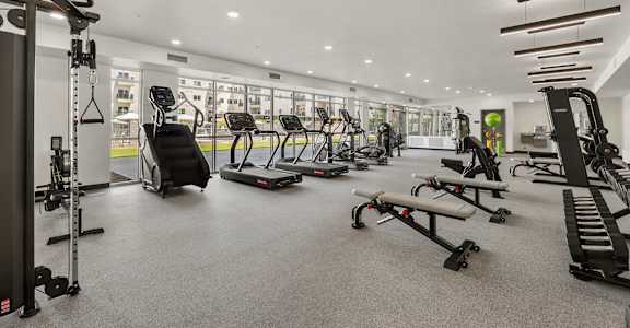 A spacious gym with a variety of equipment including treadmills, weight machines, and benches.