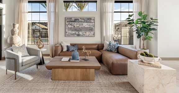 A living room with a large couch, a coffee table, and a chandelier.