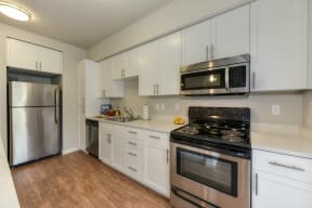 Kitchen with Wood Inspired Floors, Refrigerator, White Cabinets and Oven