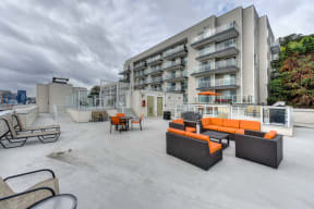 Rooftop Lounge Area with Orange Sofa, Lounge Chairs and Apartment Exterior