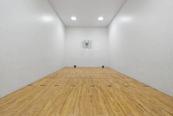 a large white room with a wooden floor and a basketball hoop on the wall