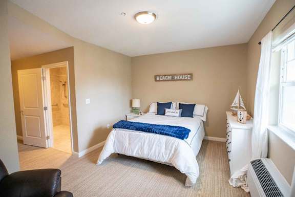 A bedroom with a bed, nightstand, and chair.