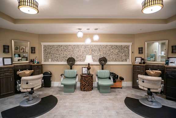 A salon with chairs and mirrors on the wall.