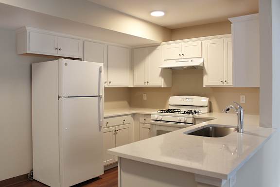 a kitchen with white cabinets and a sink and a refrigerator